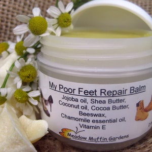 Puede incluir: Un tarro transparente de "My Poor Feet Repair Balm" con tapa blanca, rodeado de flores de manzanilla y trozos de manteca de karité. La etiqueta enumera ingredientes como aceite de jojoba y aceite esencial de manzanilla. El tarro es de 57g.
