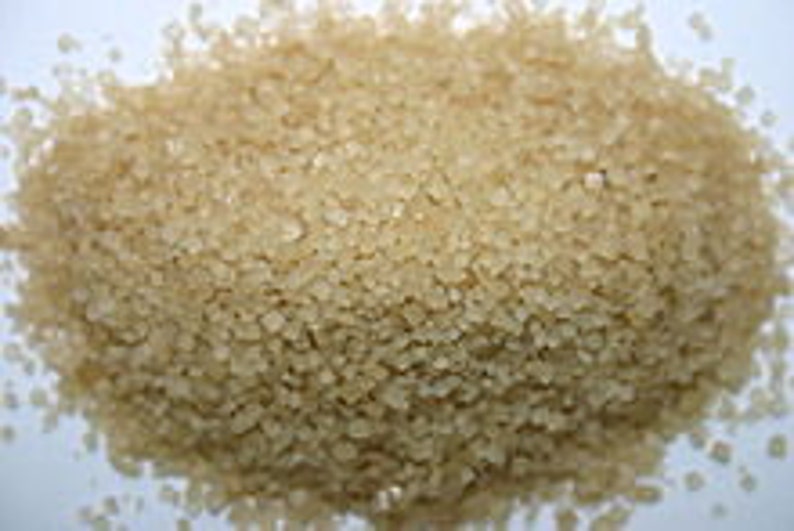 May include: A close-up view of light brown granulated sugar crystals.