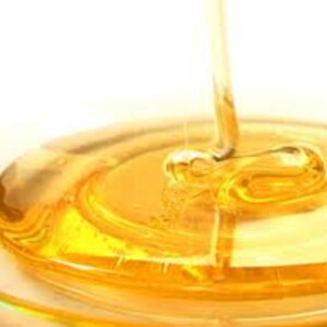 May include: Golden honey pouring into a clear glass dish, creating a swirling pattern.