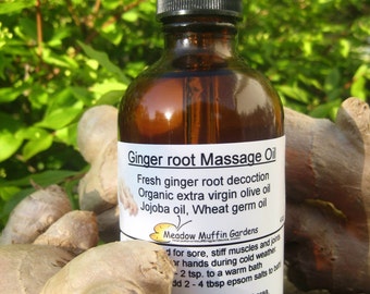 May include: A brown glass bottle with a dropper top filled with ginger root massage oil. The label reads "Ginger root Massage Oil", "Fresh ginger root decoction", "Organic extra virgin olive oil", "Jojoba oil, Wheat germ oil", and "Meadow Muffin Gardens".