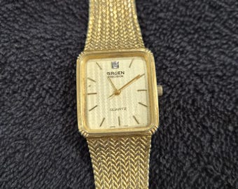 Montre à quartz dorée Gruen des années 1970 avec accent de pierres (verre manquant)
