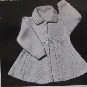 May include: A white knitted cardigan with a collar and button closure. The cardigan has a cable knit pattern and a flared skirt.