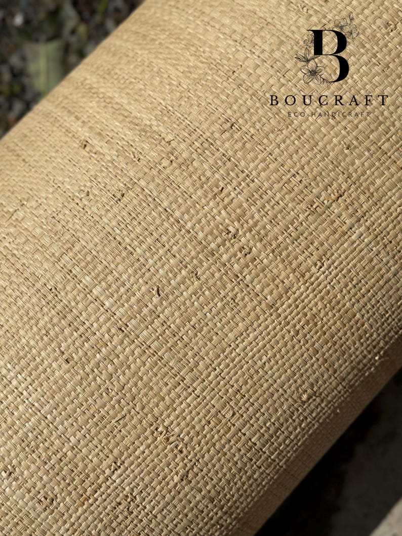 May include: Close-up of a rolled-up, woven material in a natural beige color. The texture is a tight, cross-hatched pattern. The text "BOUCRAFT ECO HANDICRAFT" is printed in black.