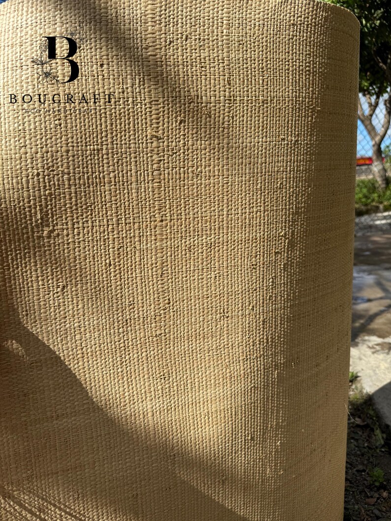 May include: Close-up of a rolled, textured, beige woven material. The material has a consistent pattern of vertical and horizontal lines, creating a grid-like appearance. The logo "BOUCRAFT" is visible in the upper left corner.