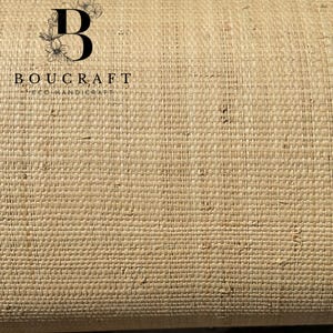 May include: Close-up of a roll of woven material in a natural beige color. The material has a textured, basket-weave pattern. The brand name "BOUCRAFT ECOHANDICRAFT" is printed in black, with a stylized "B" and floral design.
