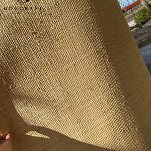 May include: A rolled-up, woven mat made of natural fibers, displaying a textured, beige surface. The mat is partially unrolled, revealing its construction. The logo "BOUCRAFT" is visible in the upper left corner.