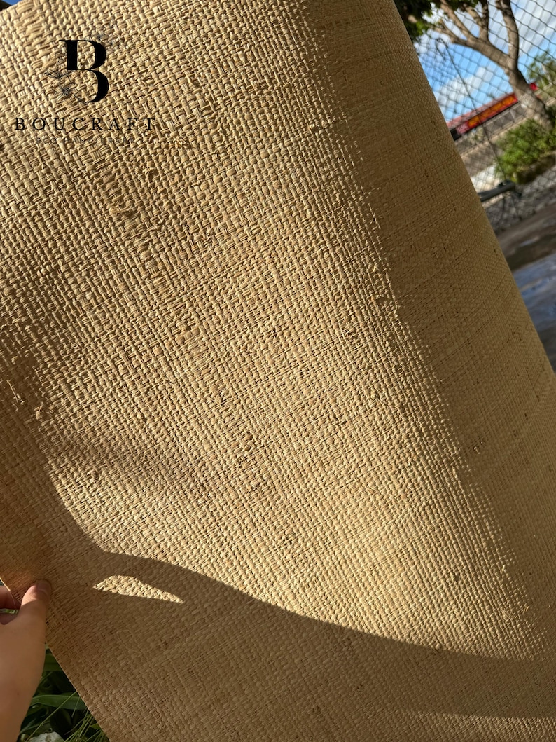 May include: A rolled-up, woven mat made of natural fibers, displaying a textured, beige surface. The mat is partially unrolled, revealing its construction. The logo "BOUCRAFT" is visible in the upper left corner.