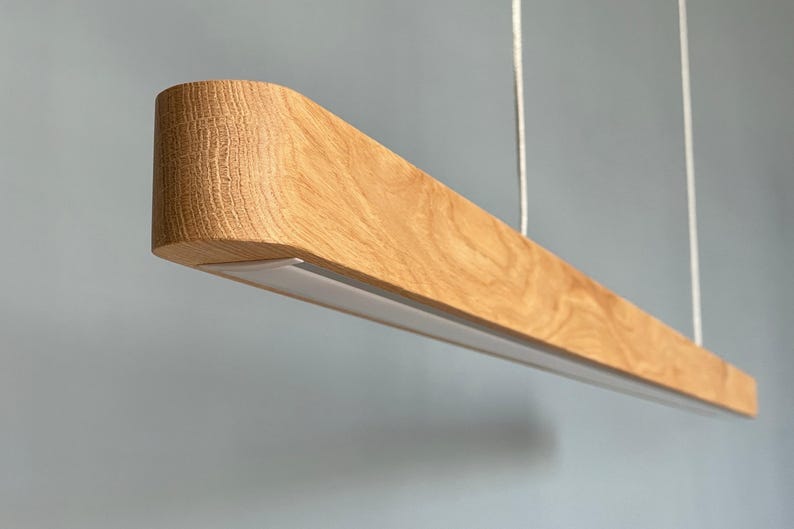 Large handmade wooden linear chandelier with LED lighting, rustic modern pendant light hanging above dining table, natural wood suspension lamp for farmhouse or modern interior.