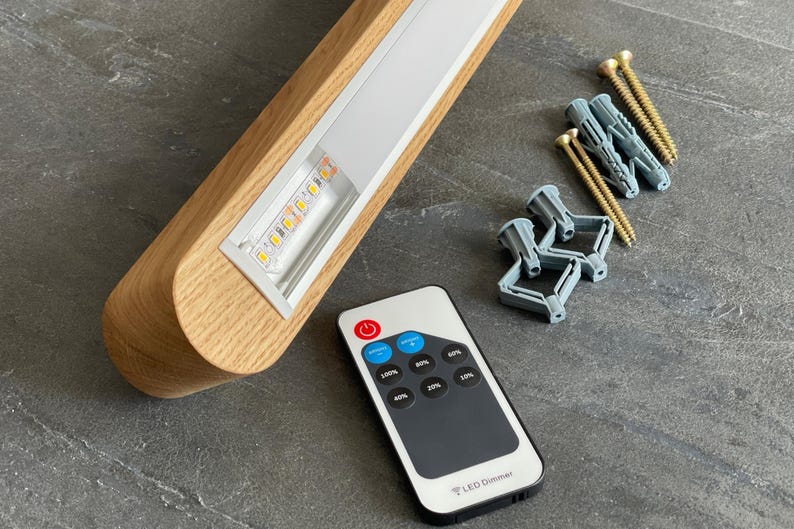 Light oak linear LED pendant light with visible LED strip, remote control, mounting hardware, and wall plugs. Complete set for easy installation and dimmable lighting control.