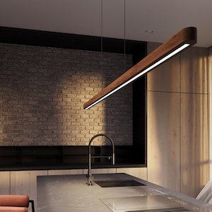 Könnte beinhalten: Moderne Küche mit einer rechteckigen Pendelleuchte aus Holz. Die Leuchte hängt von der Decke und hat eine helle, lineare Lichtquelle. Die Küche verfügt über eine Backsteinmauer, Holzschränke und eine Edelstahlarmatur.
