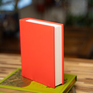 May include: A white ceramic mug with a black handle and the text "But First, Coffee" in a black, bold font. The mug is sitting on a wooden surface. The mug is approximately 4 inches tall.