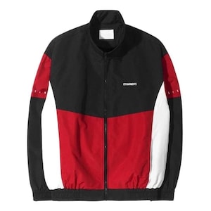 May include: A black, red, and white track jacket with a full zip. The jacket has a black upper, a red lower, and white sleeve accents. The text "STD GARMENTS" is printed on the chest. A sporty, casual garment.