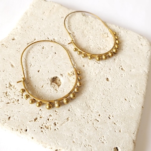 May include: A pair of gold hoop earrings with small round beads around the edge.