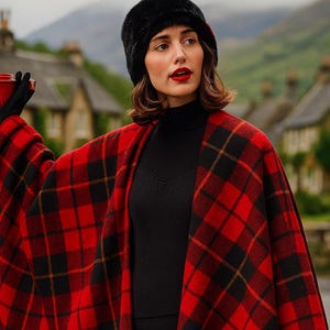 Pode incluir: Uma capa xadrez vermelha e preta com franjas, usada sobre uma gola alta e calças pretas. Um chapéu e luvas de pele pretas completam o look. O padrão da capa é um design escocês clássico.