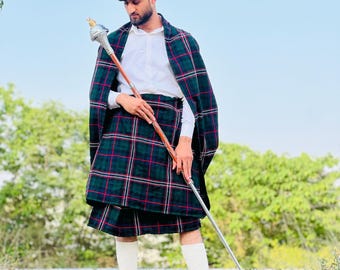 Peut inclure: Un homme portant une casquette noire, une chemise blanche, un kilt écossais vert et noir et des chaussettes blanches. Il tient un bâton en bois avec un sommet argenté.
