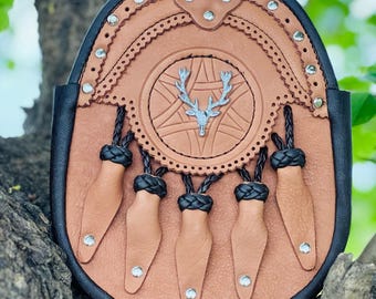 May include: A brown leather sporran with a black trim and five leather tassels. The sporran features a silver stag head emblem and decorative stitching.