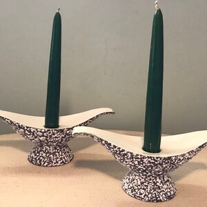 May include: Two white ceramic candle holders with a speckled brown and white glaze. Each holder has a green candle.