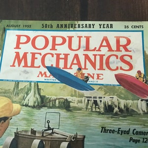 May include: A vintage cover of Popular Mechanics magazine from August 1952, featuring a blue and red boat with people in them, a man in a yellow hat, and the text "Three-Eyed Camera Page 120".