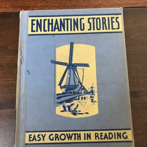 May include: A blue book with the title "Enchanting Stories" and the subtitle "Easy Growth in Reading". The cover features a yellow and blue illustration of a windmill.
