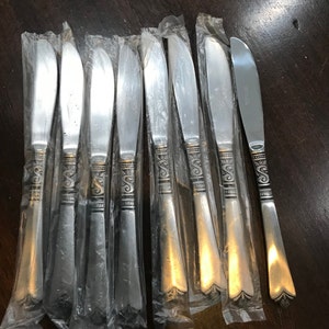 May include: A set of ten silver dinner knives with ornate handles, individually packaged in plastic.