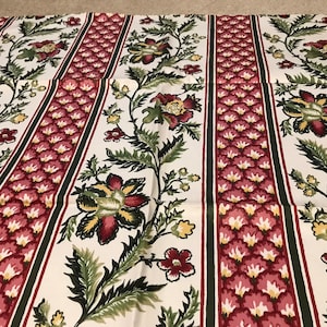 Puede incluir: Tela blanca con un patrón repetido de rayas florales rosas y verdes. El diseño floral presenta una flor estilizada con un centro amarillo y pétalos rojos.