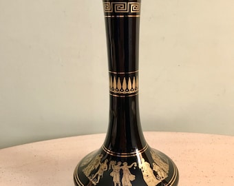 May include: Black ceramic vase with gold Greek key and floral designs. The vase features a scene of figures in gold.