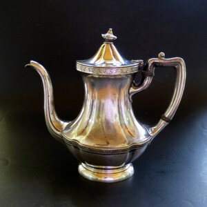 May include: A silver teapot with a decorative design and a lid. The teapot has a spout and a handle.