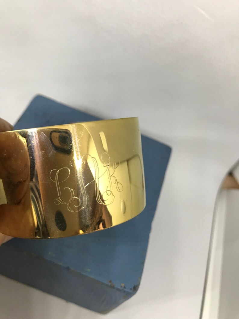 May include: A gold metal napkin ring with the initials "G.K." engraved on the front.