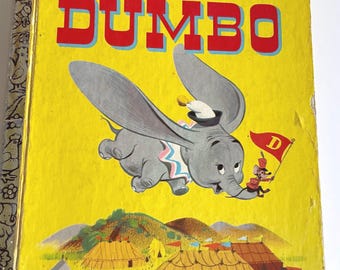 May include: A vintage Little Golden Book with a yellow cover featuring Walt Disney's Dumbo flying with a mouse holding a flag that says "D". The book has a price of 39¢ and the text "a Little Golden Book" and "WALT DISNEY'S DUMBO" on the cover.