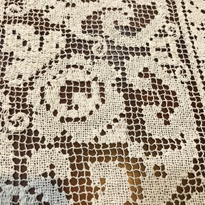 May include: White crocheted lace tablecloth with a delicate floral pattern. The lace is intricate and has a fine texture.
