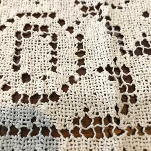 May include: White crocheted lace tablecloth with a delicate floral pattern.