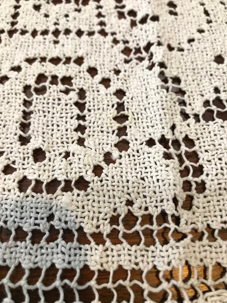 May include: White crocheted lace tablecloth with a delicate floral pattern.