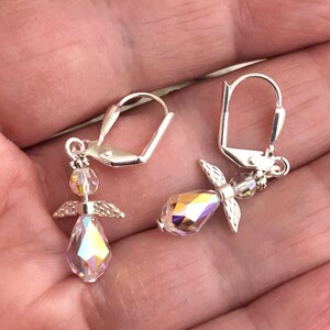 Puede incluir: Un par de pendientes de plata con forma de &aacute;ngel con detalles de cristal iridiscente. Los pendientes presentan un peque&ntilde;o dise&ntilde;o de alas de &aacute;ngel y un cristal en forma de l&aacute;grima.