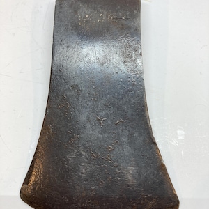 Puede incluir: Una cabeza de hacha de metal oscuro y desgastado con un filo ancho y curvo y una parte posterior plana. La superficie muestra signos de oxidación y desgaste, con la palabra "WALTERS" claramente estampada en el metal cerca de la parte superior.