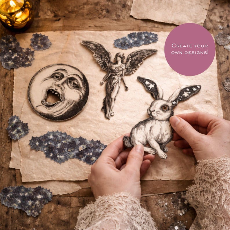 Op de afbeelding: Een set papieren uitknipsels met een maan met een gezicht, een gevleugelde engel en een konijn met oren vol sterren. De uitknipsels zijn zwart-wit illustraties. Een roze cirkel met de tekst CREATE YOUR OWN DESIGNS! is zichtbaar.