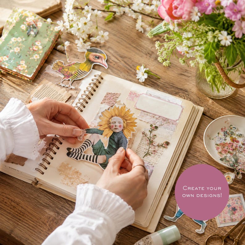 May include: A spiral-bound scrapbook featuring paper cutouts of a sunflower-headed figure and a bird, with decorative floral elements, a small dish of paper scraps, and a purple circular graphic with the text Create your own designs.