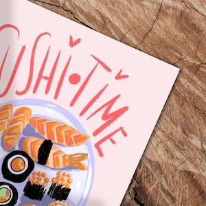 May include: A pink print featuring a plate of sushi with various pieces, including nigiri and rolls. The words "Sushi Time" are written in red above the plate. The image is set against a wooden background.