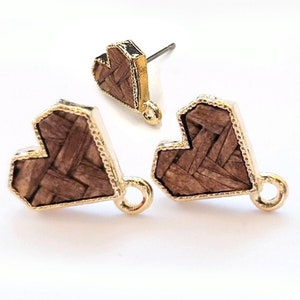 May include: A pair of gold heart-shaped earrings with a woven wood texture. The earrings have a gold loop on the back for attaching to a hook.