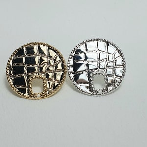 May include: Two round metal charms with a textured design. One charm is gold and the other is silver.