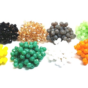 Puede incluir: Surtido de pequeñas cuentas de vidrio facetadas en varios colores, incluyendo negro, marrón, gris, verde, verde claro, blanco, naranja y amarillo.