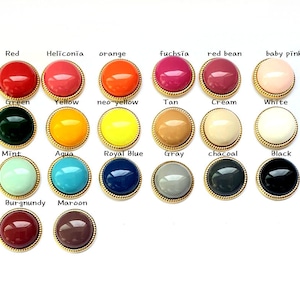 Puede incluir: Surtido de 18 botones redondos de fondo plano con ribete dorado. Los botones están dispuestos en tres filas de seis botones cada una. Los botones son de varios colores, incluidos rojo, naranja, amarillo, verde, azul, morado, rosa, marrón, negro y blanco.