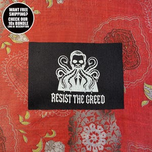 Può includere: Toppa rettangolare nera con un'illustrazione bianca di una figura con un design a forma di polpo e le parole "RESIST THE GREED". La toppa è su un tessuto rosso fantasia. Una grafica circolare in alto a sinistra dice "WANT FREE SHIPPING? CHECK OUR 10X BUNDLE LINK IN DESCRIPTION".