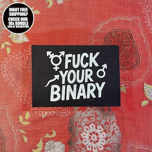Op de afbeelding: Een zwarte patch met witte tekst die luidt "FUCK YOUR BINARY" met gender symbolen. De patch ligt op een rode stof met een patroon. Een cirkelvormige afbeelding in de linkerbovenhoek zegt "WANT FREE SHIPPING? CHECK OUR 10X BUNDLE LINK IN DESCRIPTION".