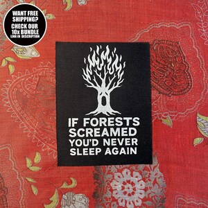 Könnte beinhalten: Ein schwarzer quadratischer Aufnäher mit einem weißen Baumdesign mit flammenartigen Blättern. Der Text "IF FORESTS SCREAMED YOU'D NEVER SLEEP AGAIN" steht unter dem Baum. Eine kreisförmige Grafik oben links lautet "WANT FREE SHIPPING? CHECK OUR 10x BUNDLE LINK IN DESCRIPTION."
