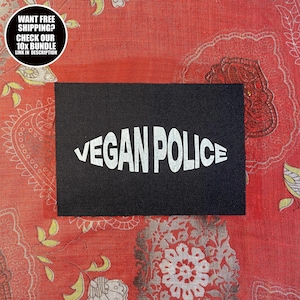 Puede incluir: Un parche rectangular negro con las palabras "VEGAN POLICE" en blanco, con una fuente curvada. El parche está sobre un fondo de tela roja estampada. Un gráfico circular en la esquina superior izquierda dice "WANT FREE SHIPPING? CHECK OUR 10X BUNDLE LINK IN DESCRIPTION."