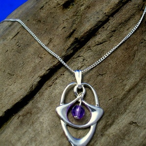 May include: A silver necklace with a pendant featuring a purple gemstone set in a silver Celtic knot design.