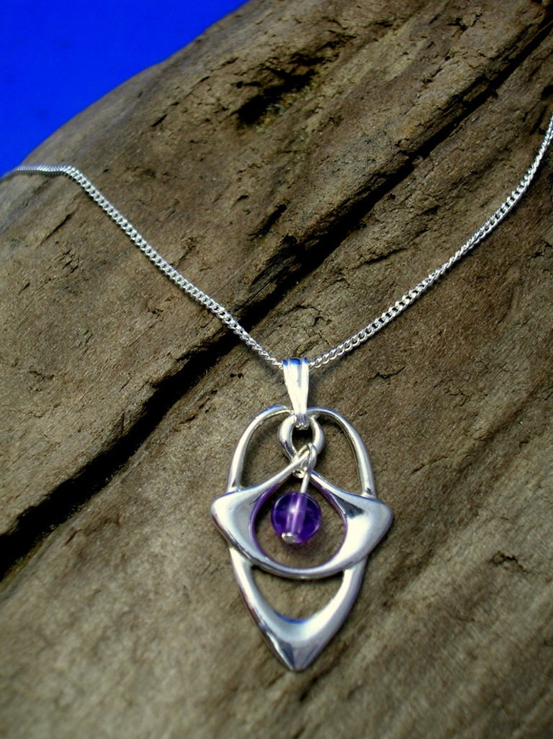 May include: A silver necklace with a pendant featuring a purple gemstone set in a silver Celtic knot design.