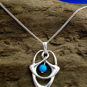 May include: A silver necklace with a pendant featuring a turquoise stone set in a geometric design.