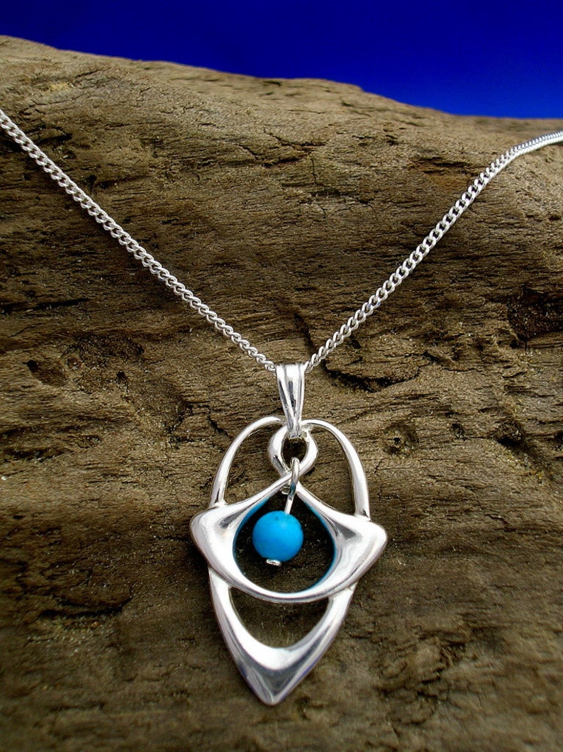 May include: A silver necklace with a pendant featuring a turquoise stone set in a geometric design.