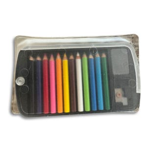 May include: A set of colored pencils in a clear plastic case. The pencils are arranged in a row, showcasing a spectrum of colors including black, purple, pink, orange, yellow, brown, white, green, blue, and teal. A pencil sharpener is visible.